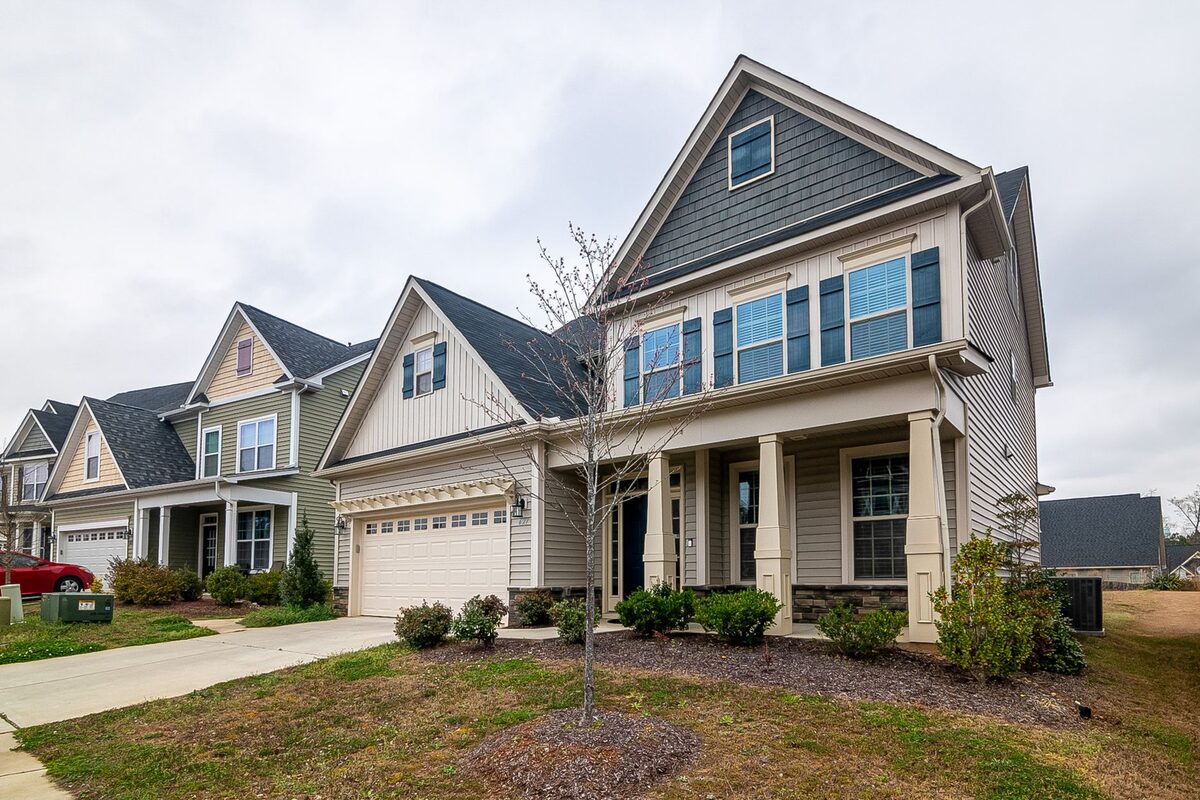 Two-story suburban home with gray shingle roof, blue and beige siding, and gutters along the rooflines